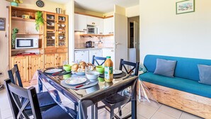 A compact living space with a dining area, kitchenette, and a blue sofa. - Les Marines de Gassin by Interhome (Gassin)