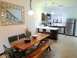 Enjoy meals in the kitchen and dining area, featuring an oven, refrigerator, and microwave, with seating for four at the wooden table.