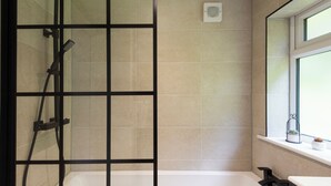 A bathroom with a shower, a bathtub, and a window.