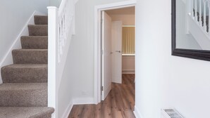 A staircase with carpeted steps leading to a room with wooden flooring and a white door.
