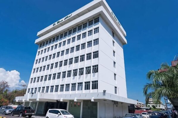Un edificio de varios pisos con fachada plana, ventanas amplias y una entrada destacada.
