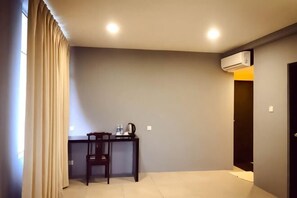 A room with a desk, chair, and an air conditioning unit.