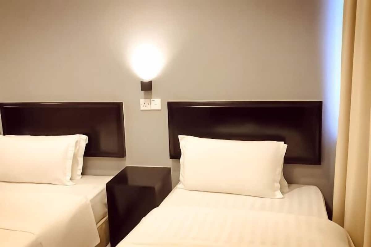 Ein Hotelzimmer mit zwei Betten, einem Nachttisch, einer Wandlampe und einer Steckdose.