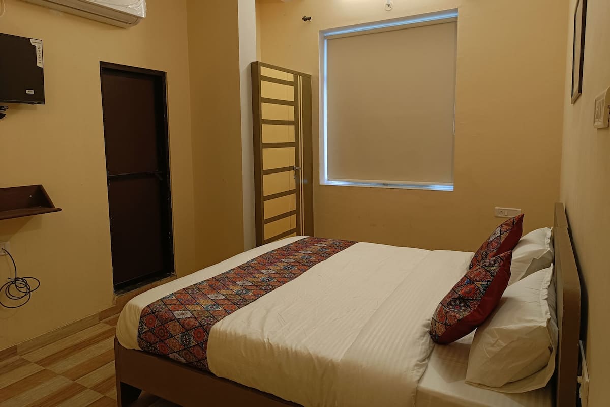 Une chambre à coucher avec un lit, une fenêtre, une porte et un appareil de climatisation.