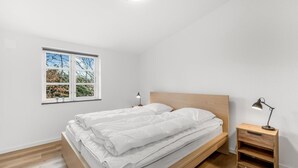 A bedroom with a bed, a nightstand, a desk, and a window with a view of trees. - "Agla" - 2.5km from the sea by Interhome (Nørre Nebel)