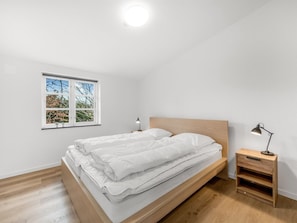 A bedroom with a bed, a nightstand, a desk, and a window with a view of trees. - "Agla" - 2.5km from the sea by Interhome (Nørre Nebel)