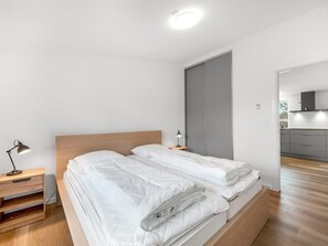 A modern bedroom with a wooden bed, bedside tables, and a view into the kitchen. - "Agla" - 2.5km from the sea by Interhome (Nørre Nebel)