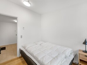 Un dormitori amb un llit, una taula de treball i una cadira.