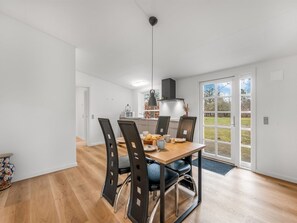 Ein Essbereich mit einem Holztisch, schwarzen Stühlen und einer hängenden Pendelleuchte.