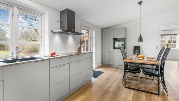 A modern kitchen with a built-in oven, a dining area with a table and chairs, and a view of the outdoors through large windows. - "Agla" - 2.5km from the sea by Interhome (Nørre Nebel)