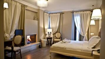 A hotel room with a bed, a television, a fireplace, and a desk with a chair.