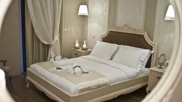 Una cama bien hecha con almohadas y una manta, una mesita de noche con lámpara, y un espejo.