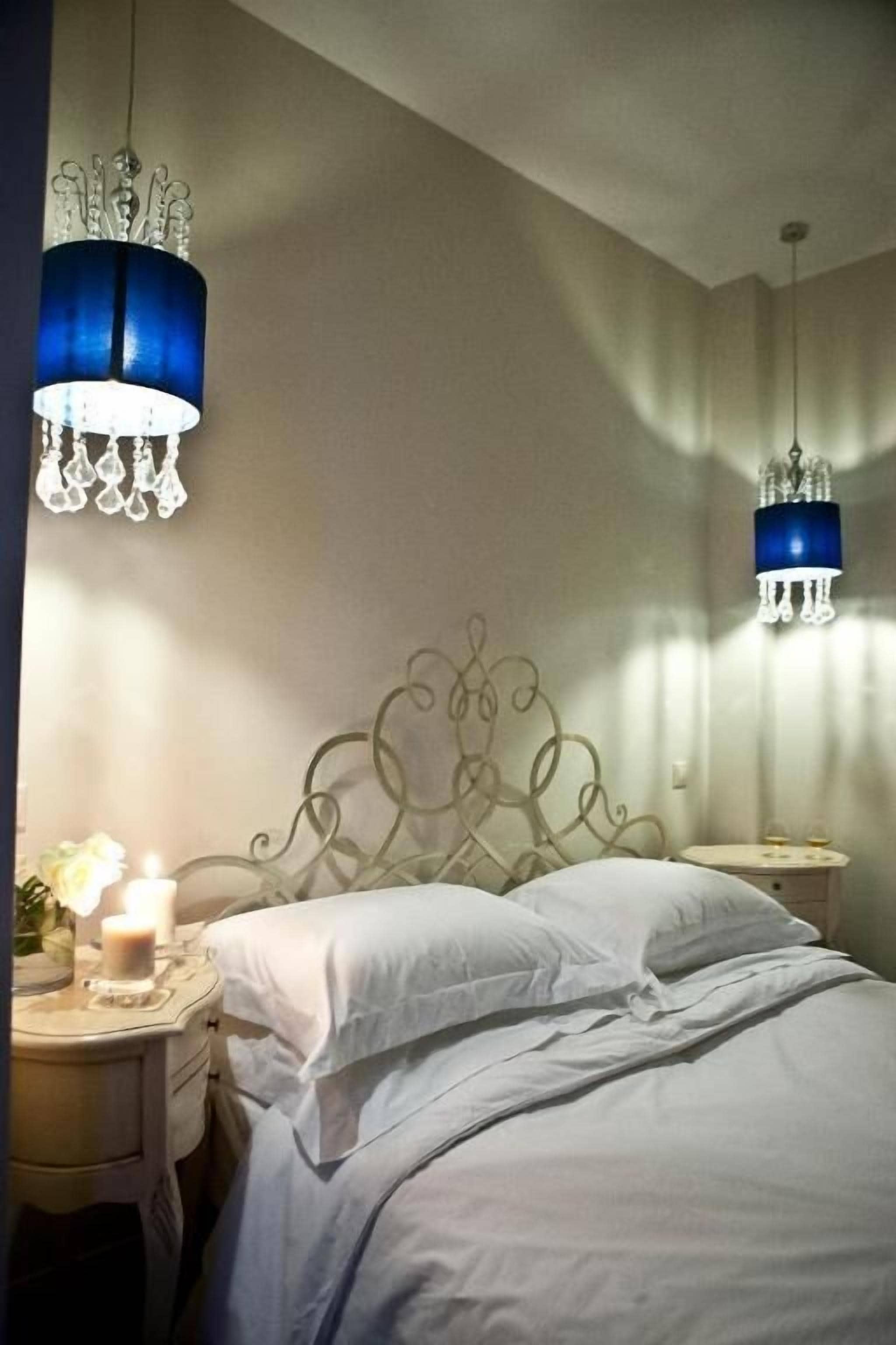 Un dormitorio con cama, mesitas de noche y dos lámparas colgantes.