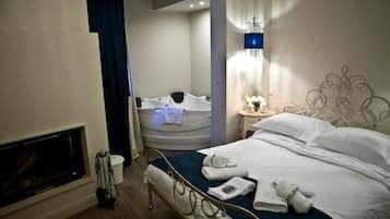 Una habitación de hotel con cama, bañera, chimenea y mesita de noche con lámpara.