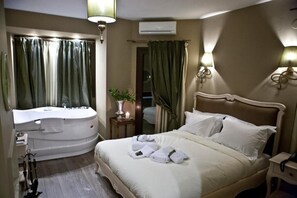 A hotel room with a large bed, a separate bathtub, a vanity with a mirror, and two wall-mounted lamps. - Melies Boutique Hotel (Almopia)