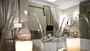 Habitación de hotel con cama, mesita de noche con lámpara, televisión y espejo en la pared.