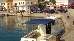 A small boat docked at a waterfront with a covered seating area and a small cabin. - Apartment in Silo/insel Krk 13424 (Dobrinj)