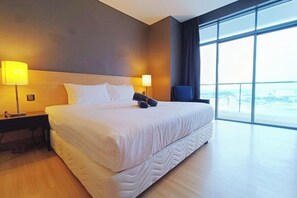 A hotel room with a large bed, two bedside lamps, a chair, and a large window offering a view.