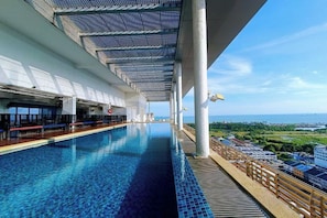 Pool auf einem Kreuzfahrtschiff mit Blick auf das Meer und eine Stadtlandschaft.