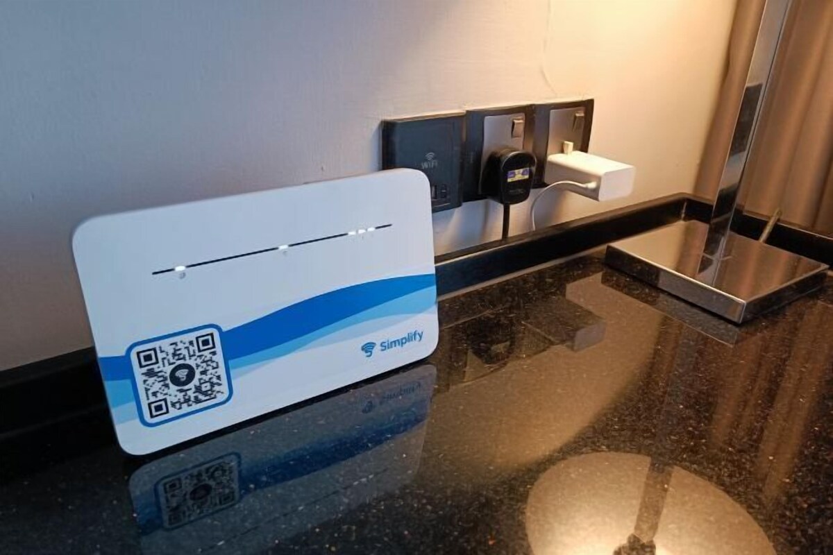 Ein QR-Code auf einer weißen Karte mit dem 'Simplify'-Logo, einem WLAN-Symbol und einer Ladestation.
