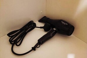 Ein schwarzer, tragbarer Heizkörper mit Kabel und Netzteil, platziert auf einem gefliesten Boden.
