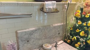 Une salle de bain avec un lavabo en marbre, un porte-serviettes, un support pour le papier toilette et un sapin de Noël décoré de canards.