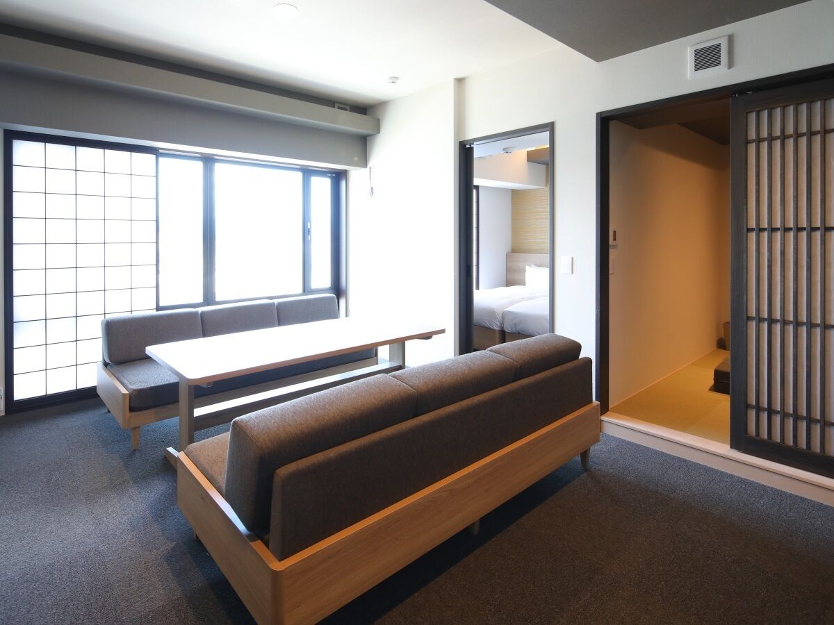 Una habitación moderna con un sofá, una mesita y una puerta corrediza que da a un dormitorio.
