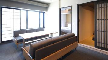 Una habitación moderna con un sofá, una mesita y una puerta corrediza que da a un dormitorio.