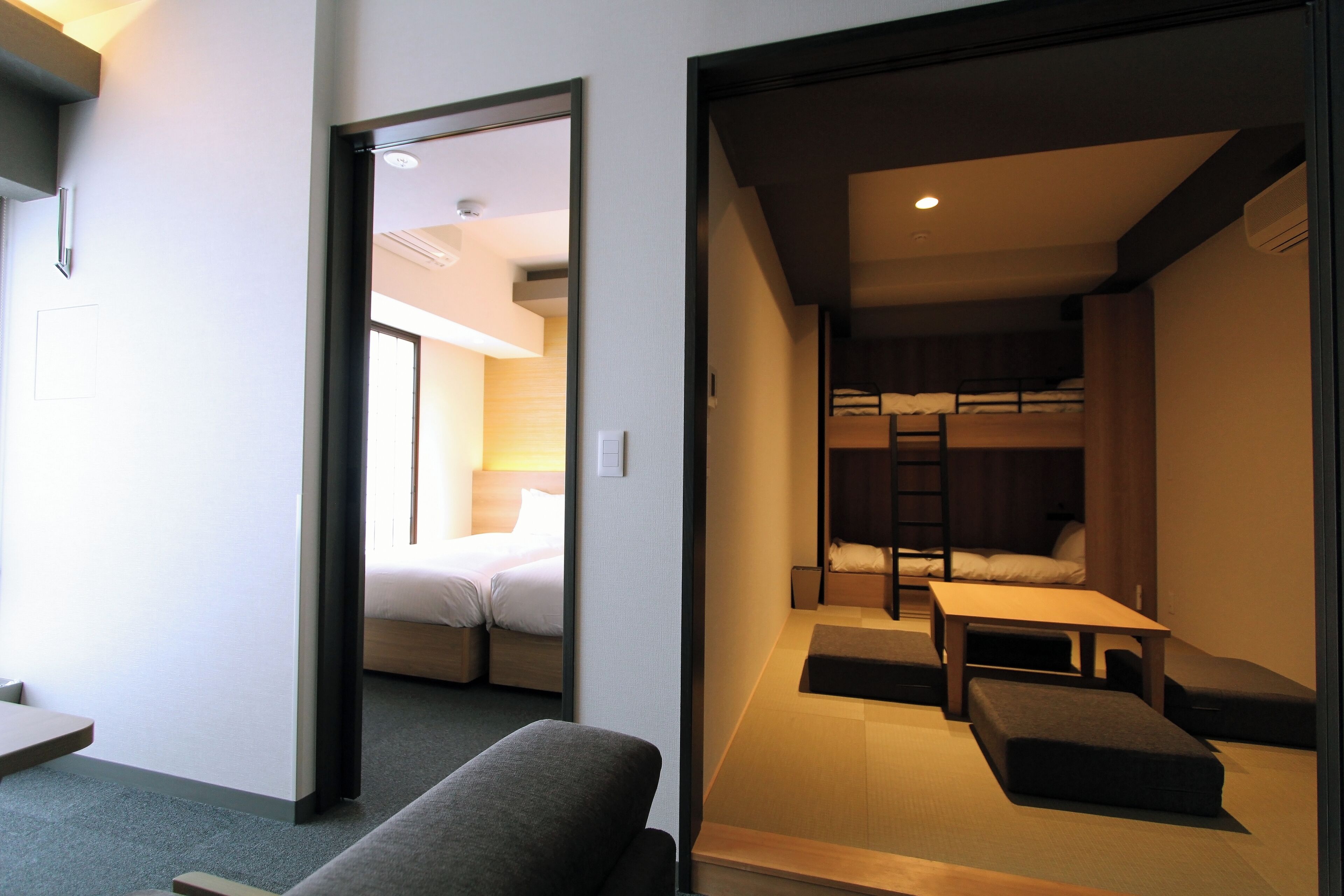 A modern hotel room with a sofa, a small table, and a bunk bed.