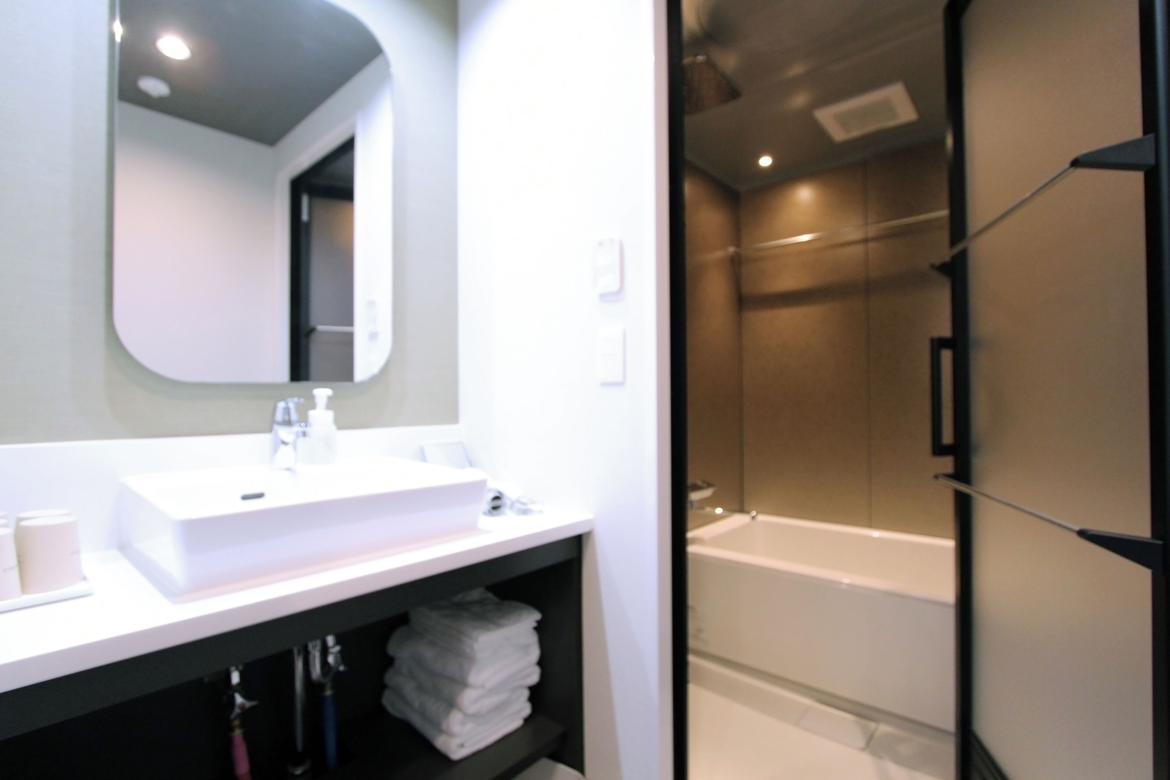 A bathroom with a white sink, mirror, and a glass-enclosed shower area.