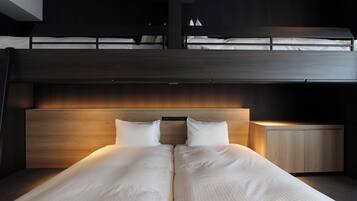 A modern hotel room with a bunk bed, a wooden headboard, and a bedside table with a lamp.