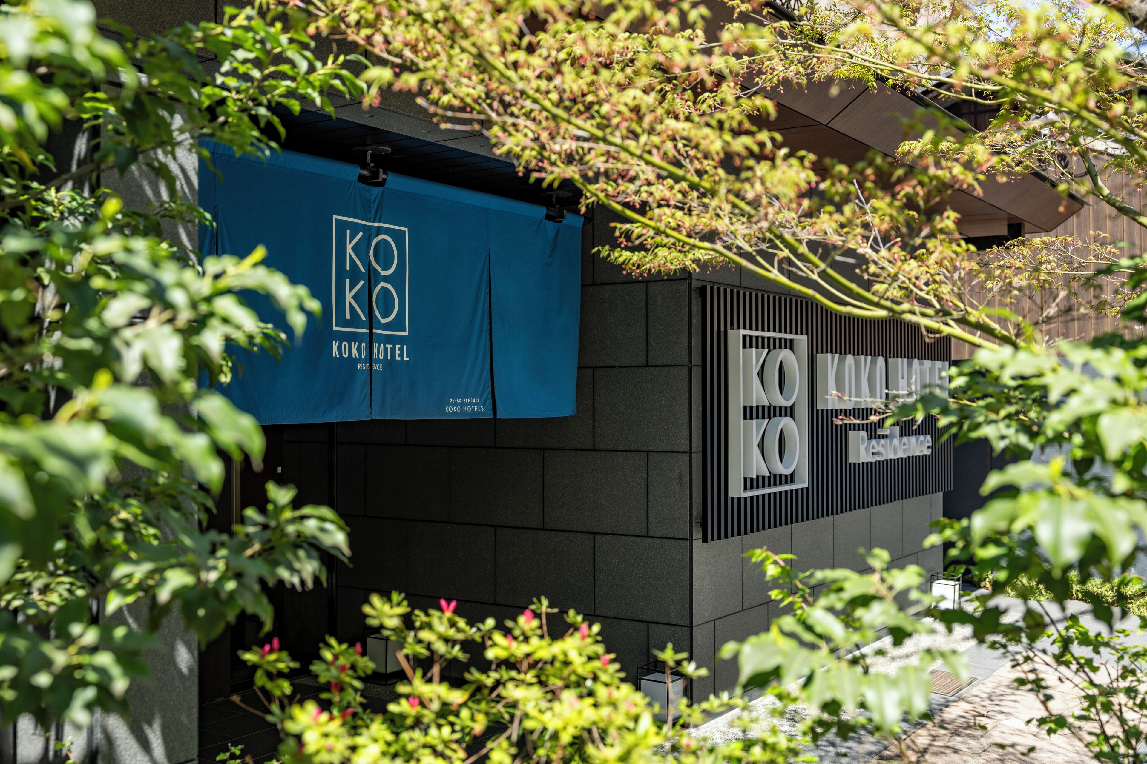 A building with a blue banner displaying 'KOKO HOTEL' and a sign with 'KOKO RESTAURANTE' on the side.