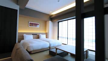 Habitación de hotel moderna con una cama grande, un sofá, una mesita y un ventanal con vistas.