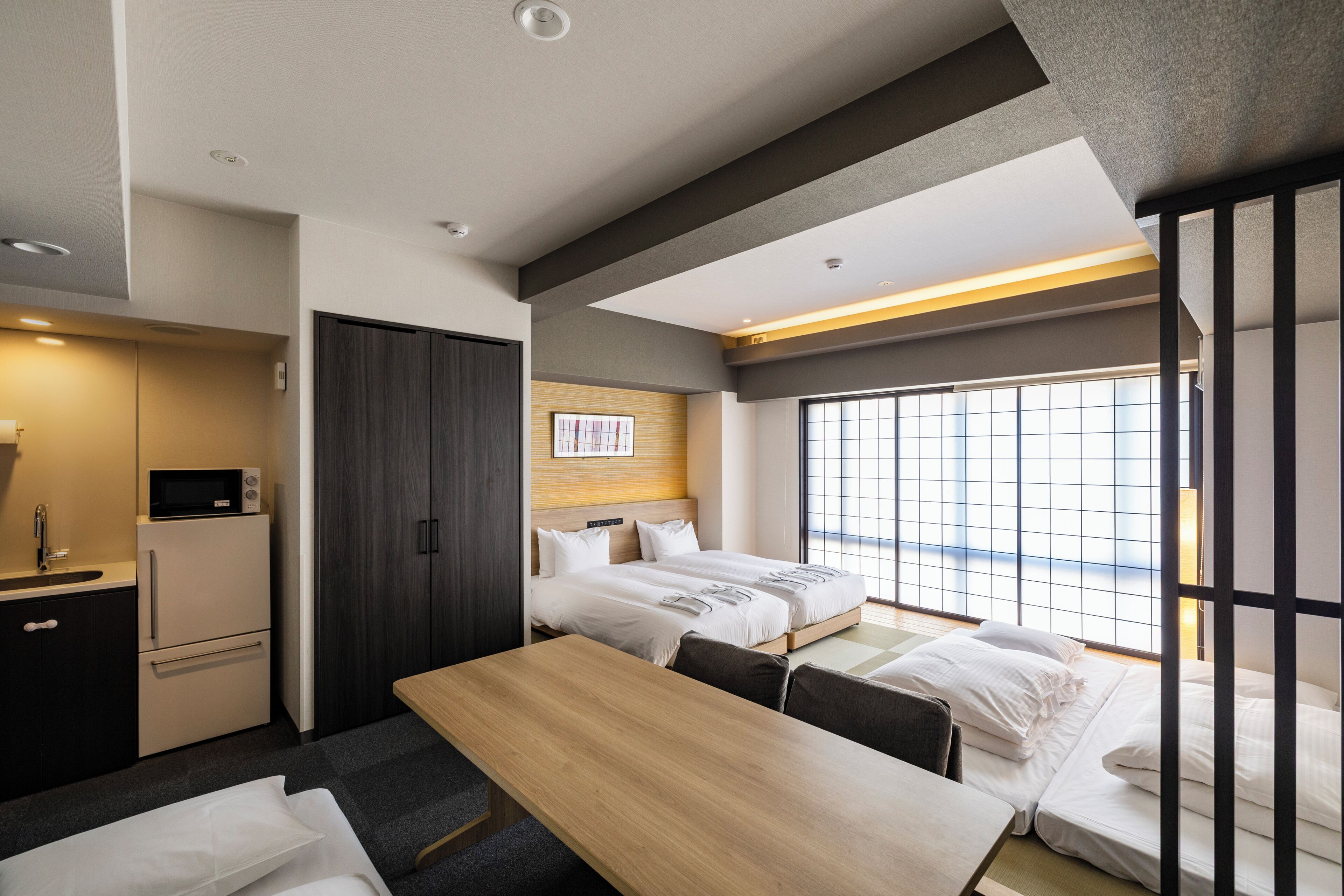 A hotel room with a bed, a desk, a microwave, a refrigerator, and a window with a view.