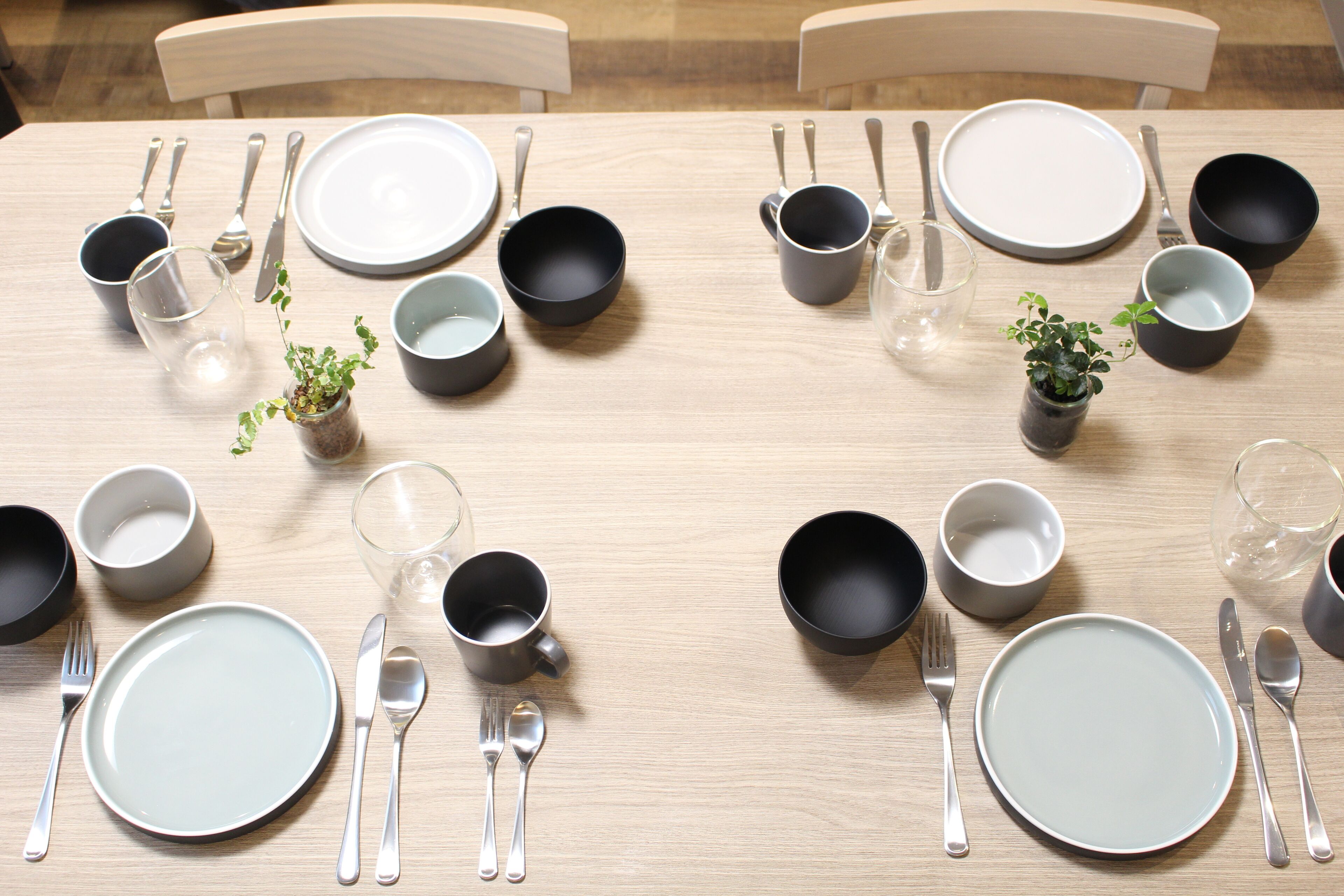 A dining table set with plates, bowls, cups, and cutlery.