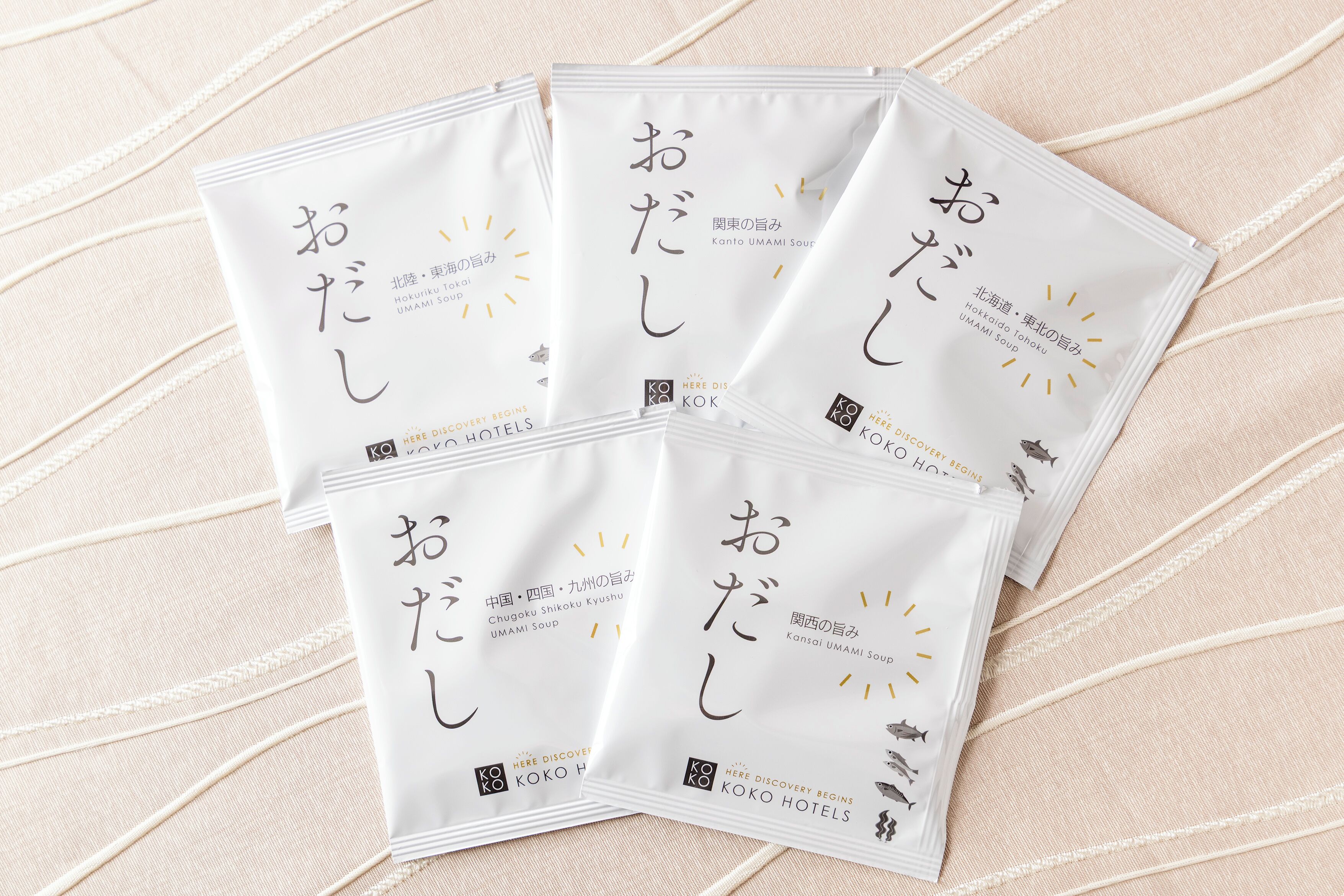Cuatro bolsas blancas con texto en japonés y el logotipo de 'KOKO HOTELS'.