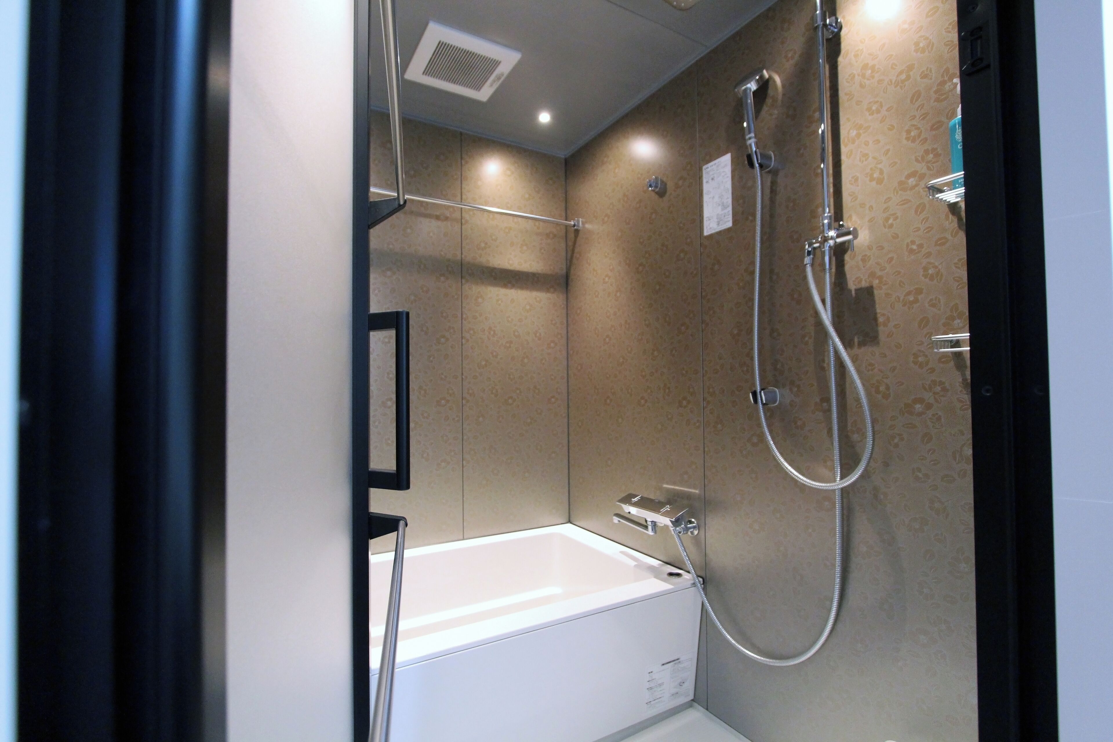 A modern bathroom with a bathtub, shower, and a towel rack.