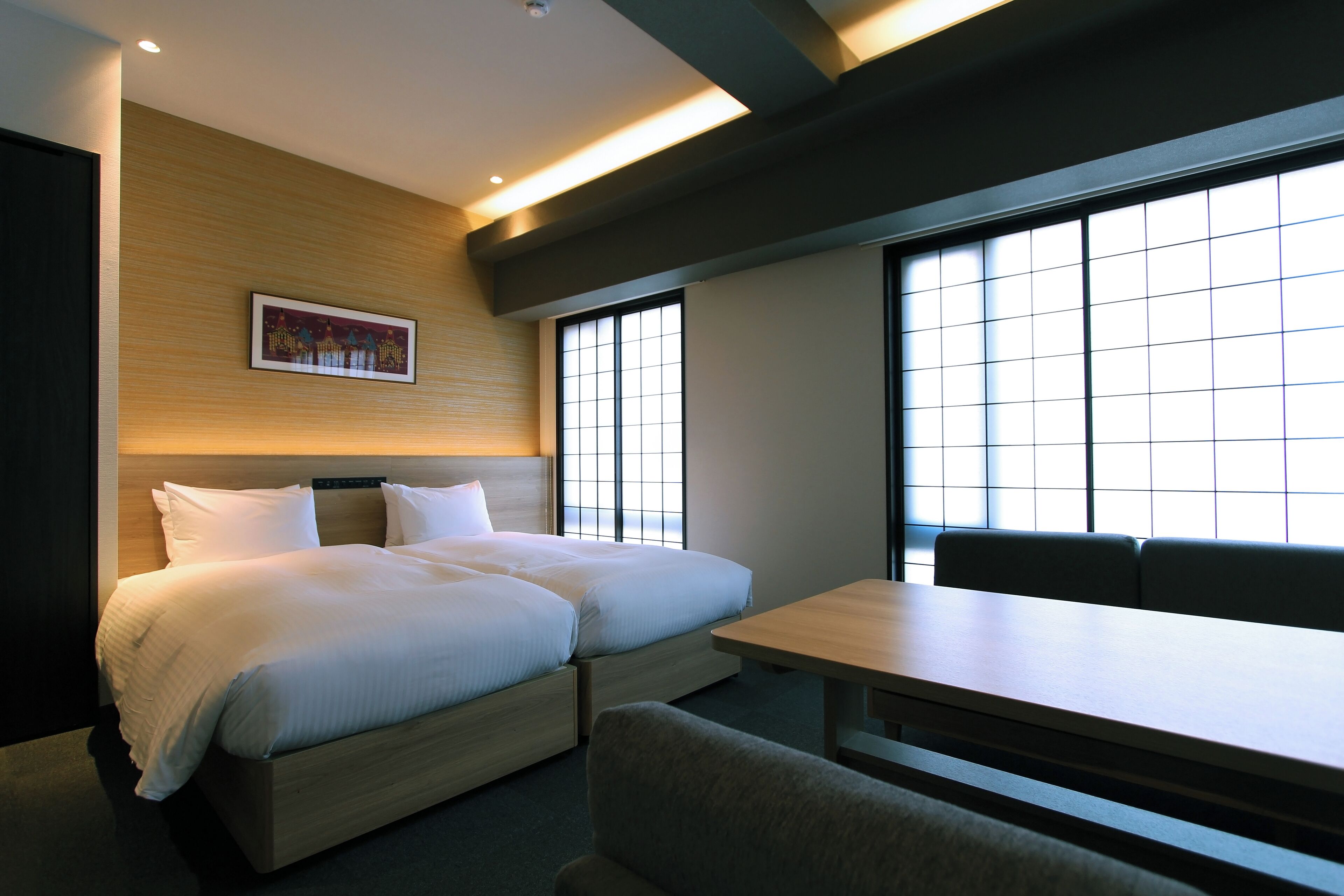 A hotel room with a bed, a desk, and a window.