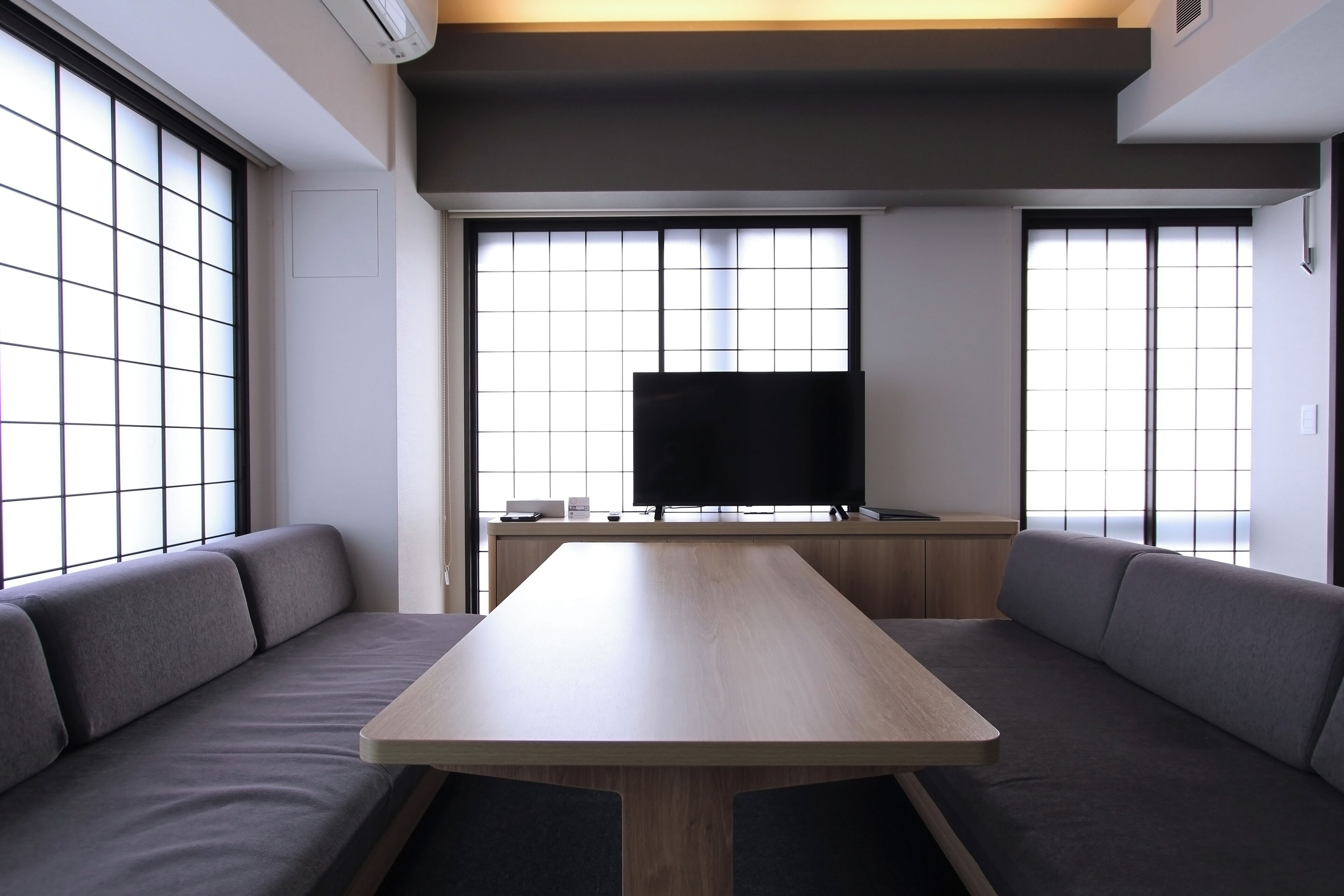 Una habitación moderna con una mesa de madera y asientos tapizados en gris.