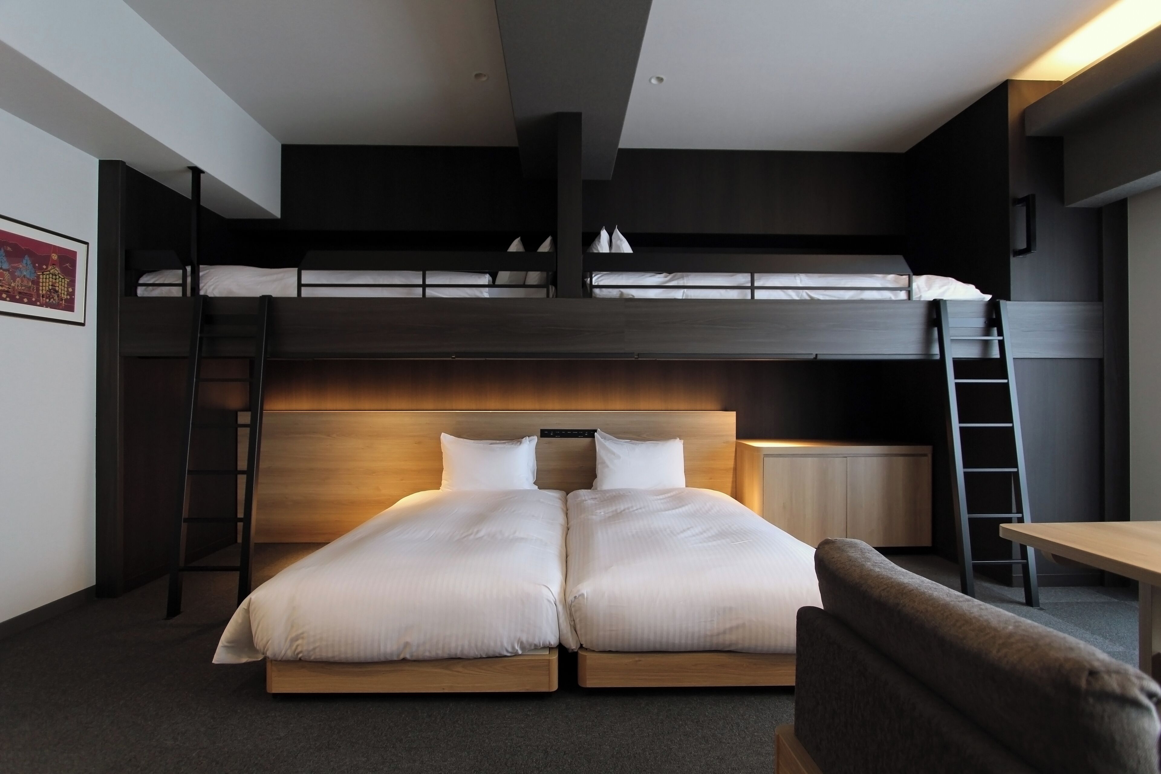 A modern hotel room with a bunk bed, a desk, and a chair.