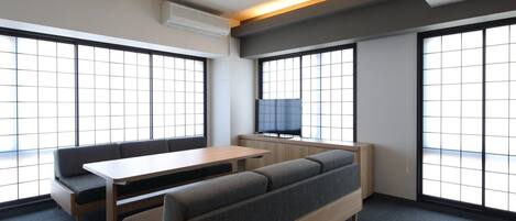 Una habitación moderna con sofá, mesa y televisor.