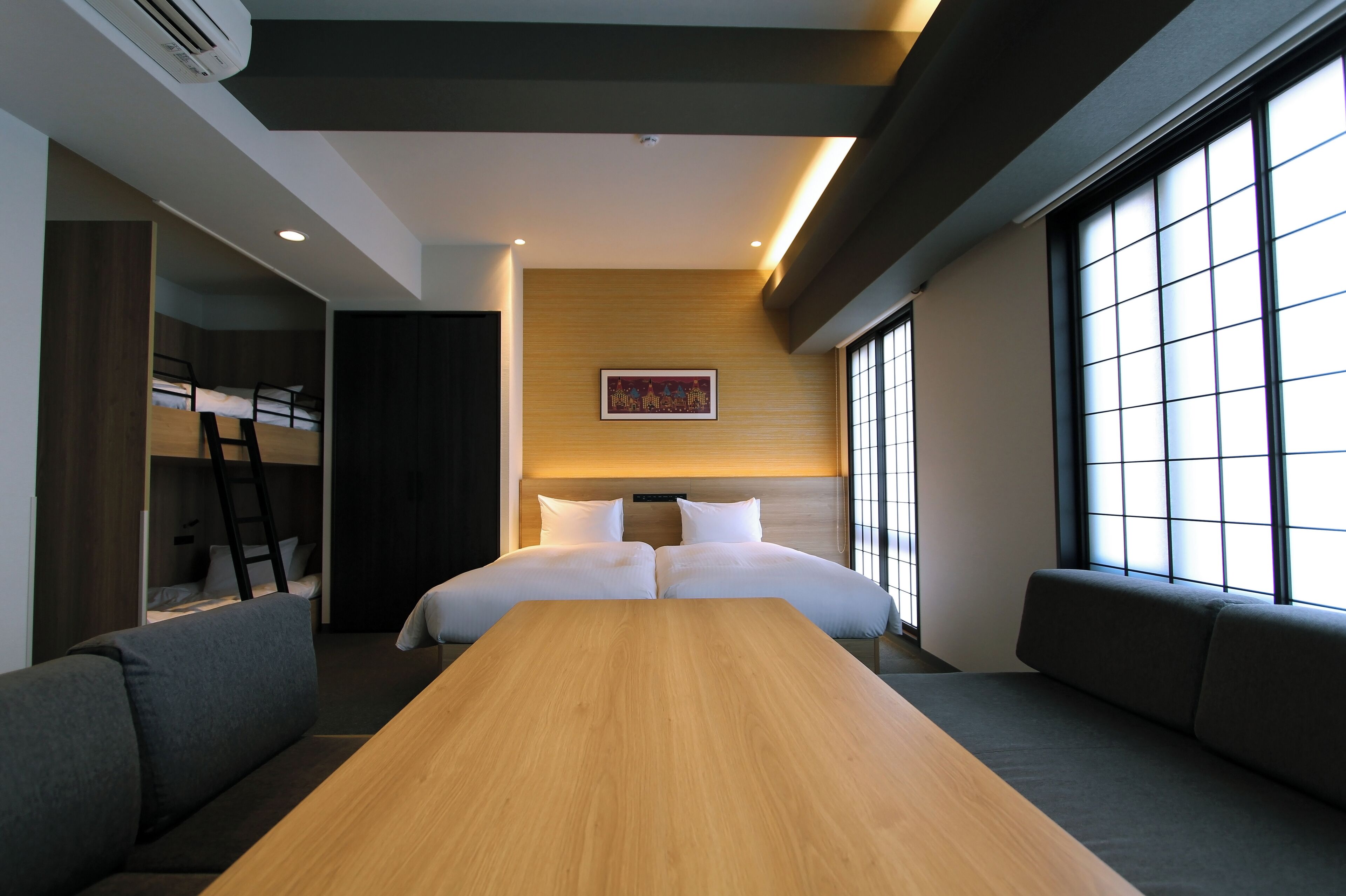 A modern hotel room with a large bed, a wooden table, and a sofa.