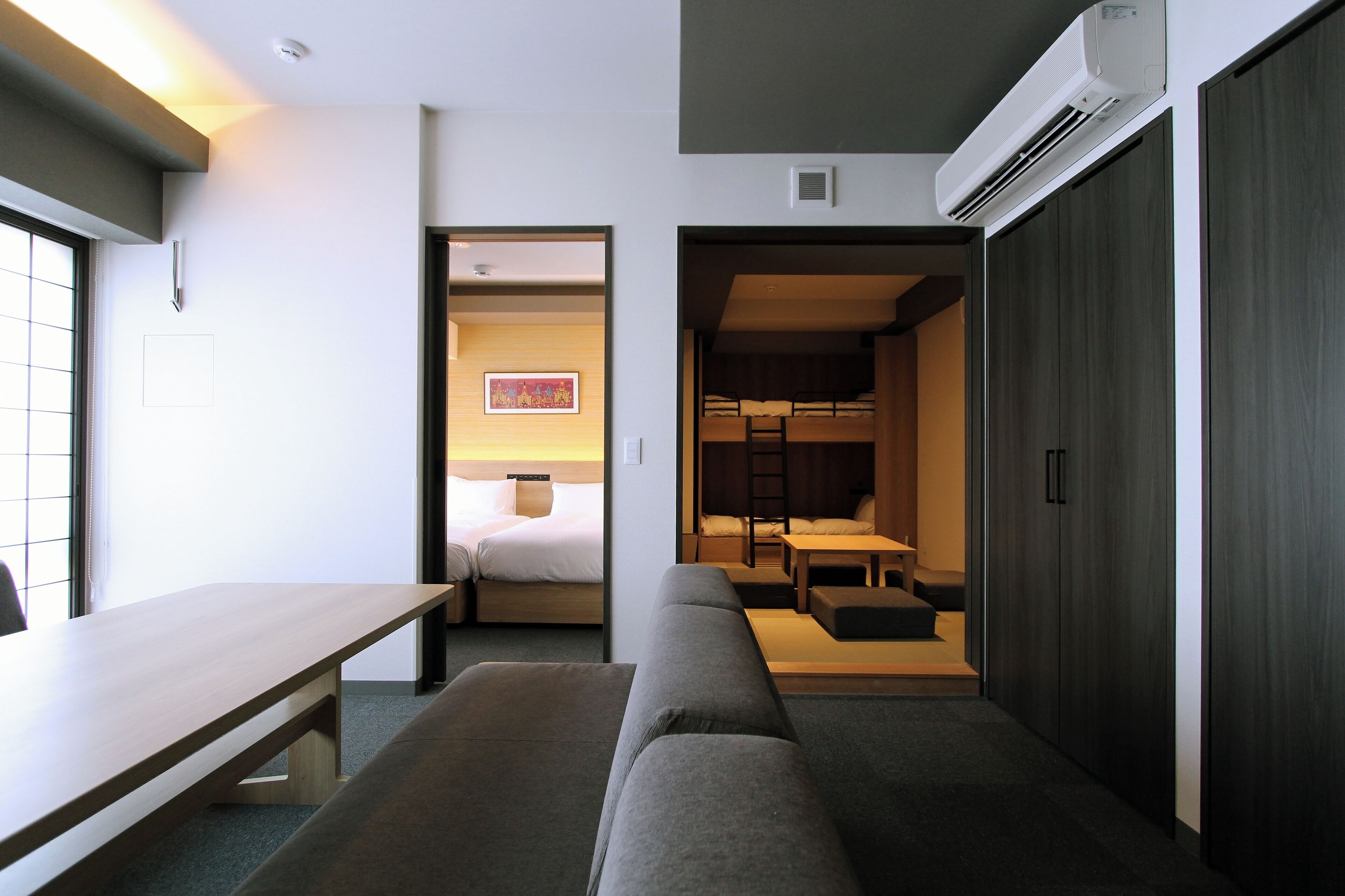 Una habitación de hotel moderna con un escritorio de madera, un sofá, una cama y una pequeña zona de comedor.