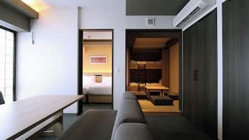 Una habitación de hotel moderna con un escritorio de madera, un sofá, una cama y una pequeña zona de comedor.