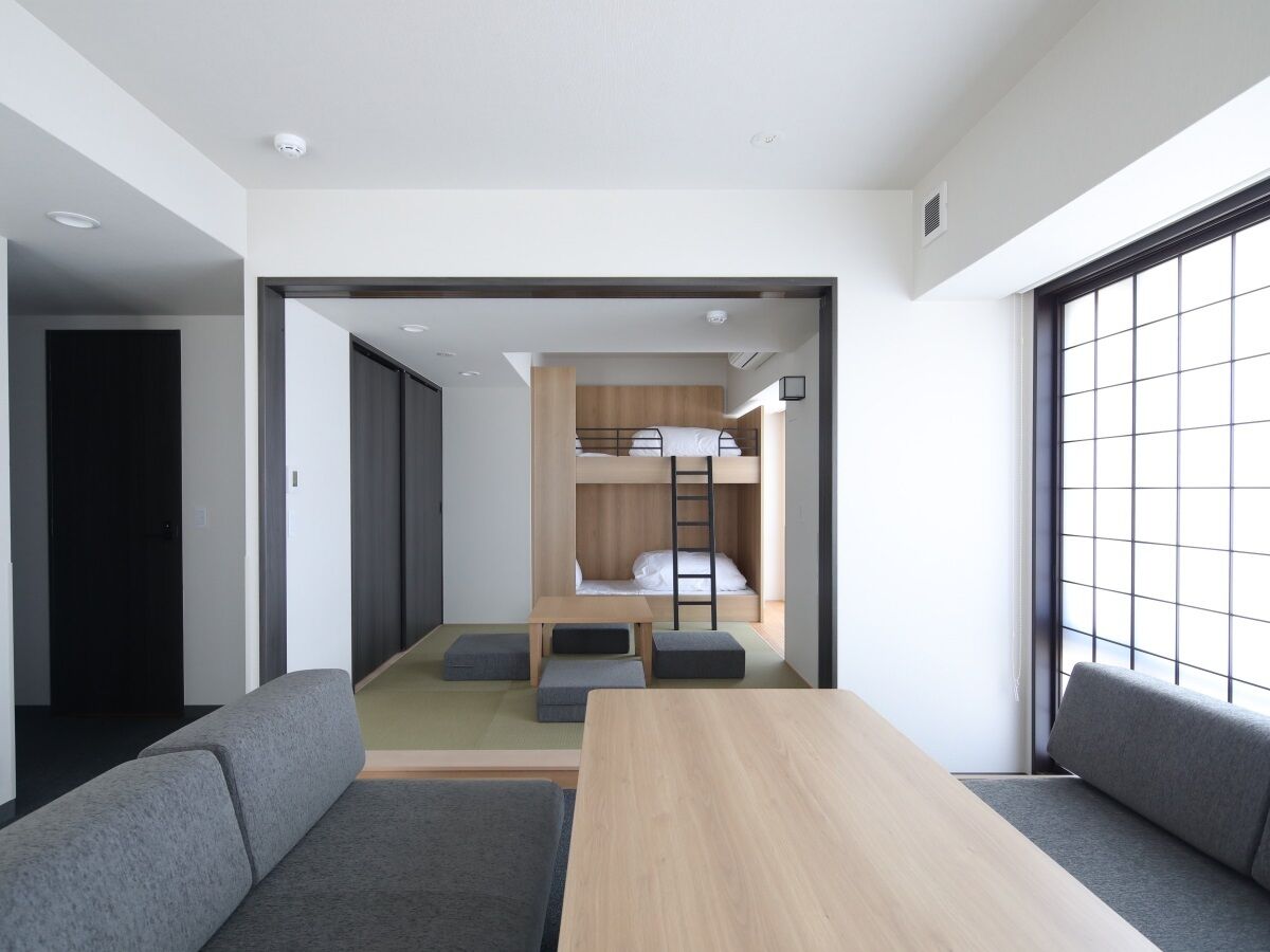 Een moderne, minimalistisch ingerichte kamer met een stapelbed, een klein tafeltje en een slaapbank.