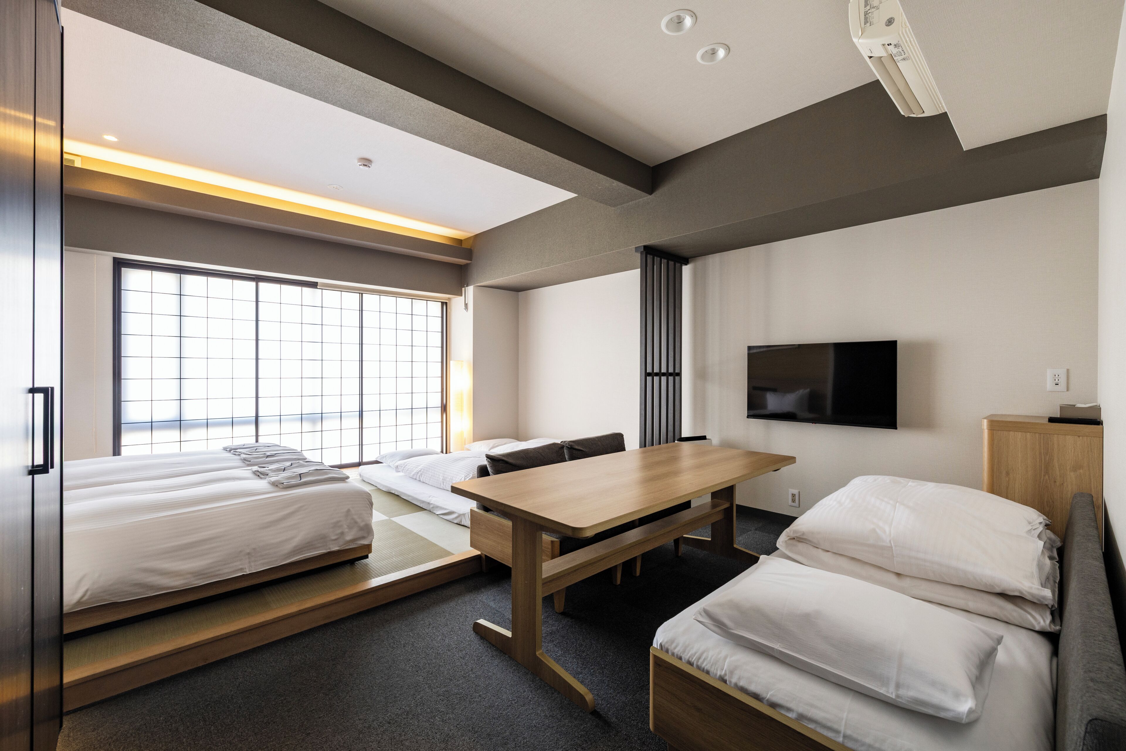 Ein modernes Hotelzimmer mit Bett, Schreibtisch, Fernseher und großem Fenster.