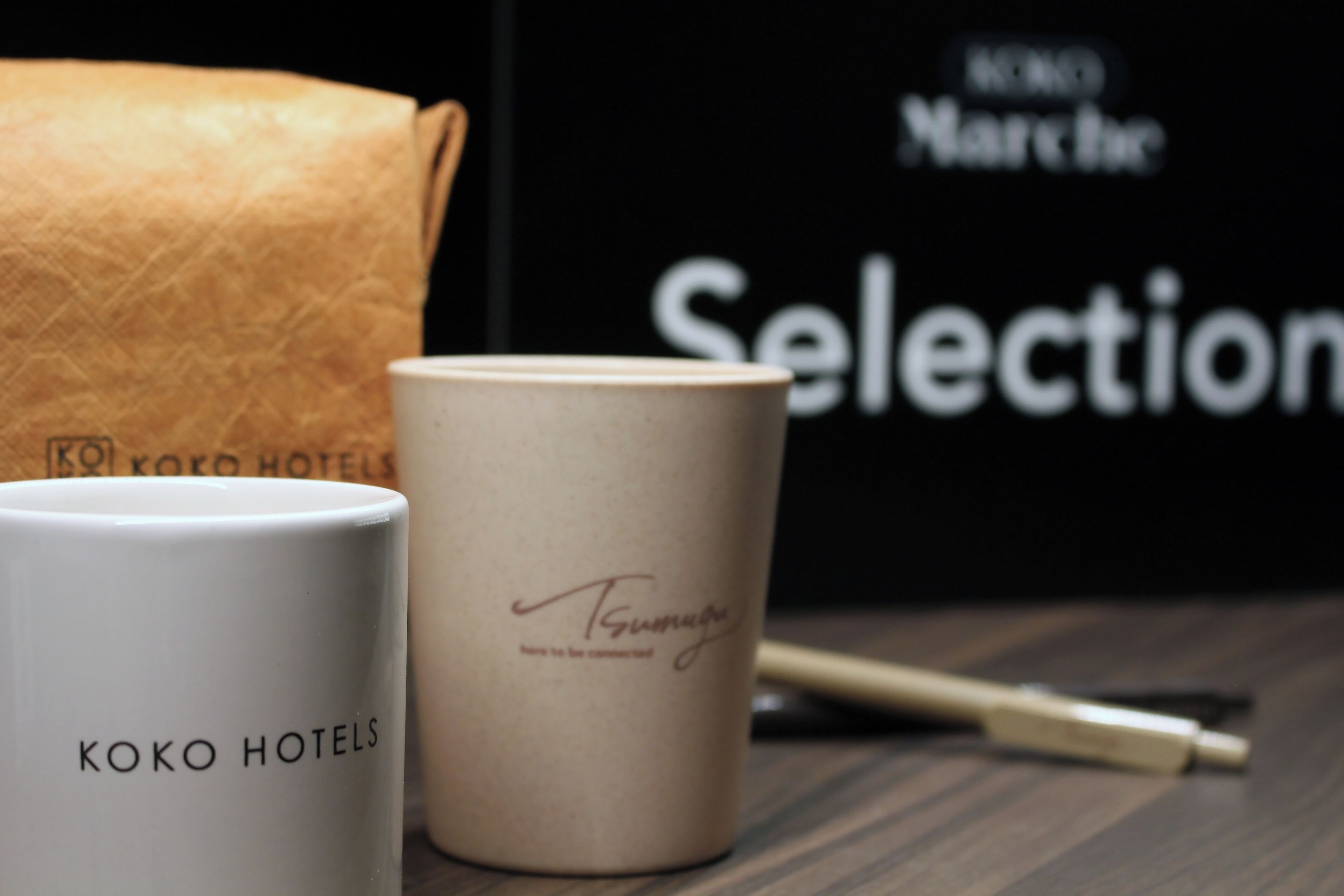 Duas canecas brancas, uma delas com a inscrição 'KOKO HOTELS' e a outra com uma assinatura.