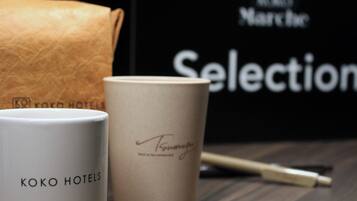 Duas canecas brancas, uma delas com a inscrição 'KOKO HOTELS' e a outra com uma assinatura.