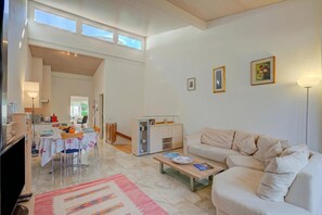 A spacious living area with a sofa, a coffee table, and a dining table set for four. - Miralago Lakeview Morcote With Pool (Morcote)