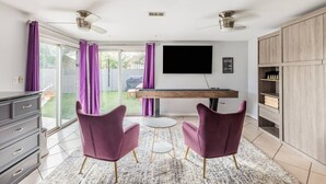 A modern kitchen with a dining area, a TV, and a view of the backyard. - Great 4 Groups, Near Everything! (Phoenix)